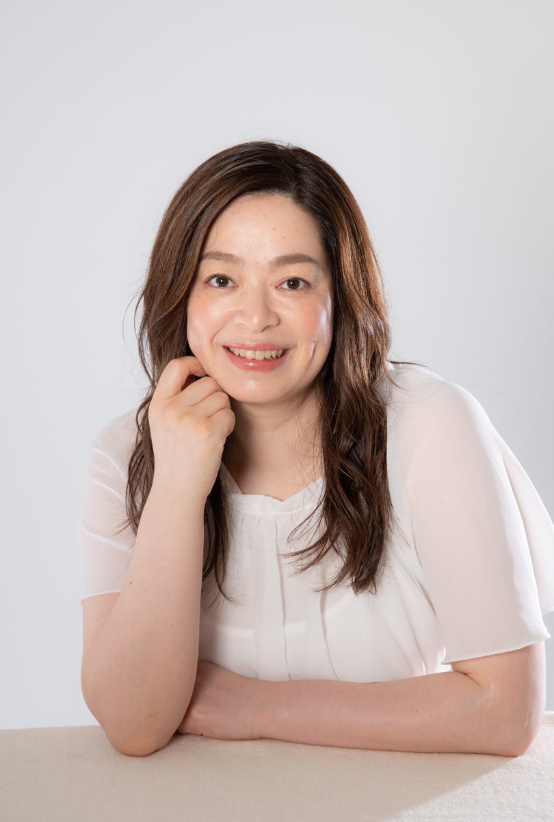 頬杖をついてほほえむ、白いブラウスのはなるり